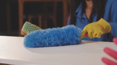 Evde elinde süngerle lastik eldivenli bir kadın var.