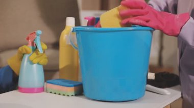 Kadının elleri kovayı tutarken evde temizlik malzemesi vardı.