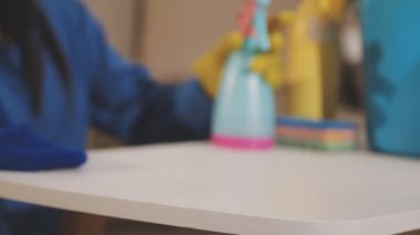 Sarı eldivenli kadın mutfak masasını temizliyor.