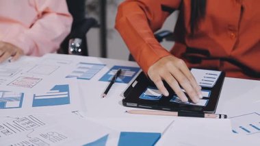 İş ekibi yeni projeyi tartışıyor ve dijital tablet üzerindeki verileri analiz ediyor