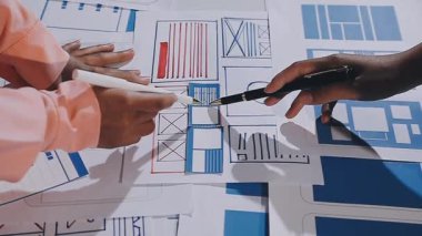 Genç mimar planlar ve planlarla, proje planlarıyla ve kağıt üzerine çizimlerle ofiste çalışıyor.