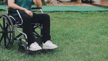 Çimlerin üzerinde tekerlekli sandalyedeki engelli adam.