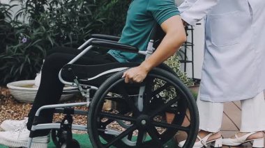 Tekerlekli sandalyeli kadın engelli arkadaşıyla yürüyor.