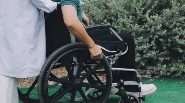 Tekerlekli sandalyede yürüyen engelli adam.