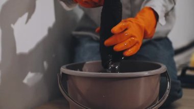 Elinde kova ve fırça olan siyah üniformalı bir adam.