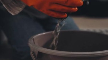 Siyah gömlekli, beyaz şapkalı ve eldivenli bir adam elinde metal bir boru tutuyor..