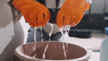 Kapalı - siyah önlüklü bir adamın elleri, spatulayla bir kâseyi yıkıyor.