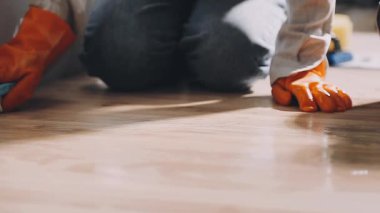 Beyaz tişörtlü adam yerleri yıkıyor.