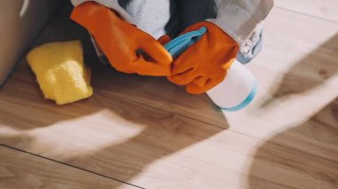 Koruyucu eldivenli kadın yerleri temizliyor.