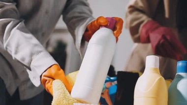 Adam sprey şişesi ve temizlik ürünleriyle ev işi yapıyor.