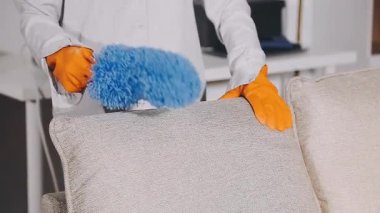 Mavi eldivenli kadın ve oturma odasındaki sarı ceketli kanepe.