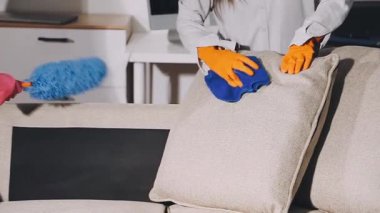 Eldivenli kadın oturma odasında bez parçasıyla masayı temizliyor.