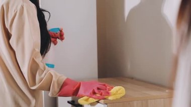 Mutfakta ev işi yapan genç bir kadın, ahşap bir tahtayla mobilyaları temizleyen bir ev kadını.