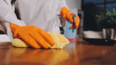 Mutfakta bir bez parçasıyla ahşap bir masayı tutan bir kadının eli.