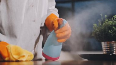 Paçavra ve spreyle eldivenli ev hanımı.