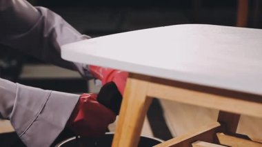 Marangoz atölyede ahşap tahtayla çalışıyor.