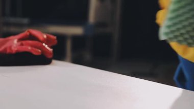 Beyaz arka planda fırçası olan eldivenli bir işçi.