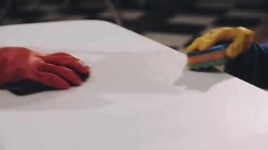 Koruyucu eldivenli ve koruyucu maskeli işçiler bir fabrikada masanın üstünde.