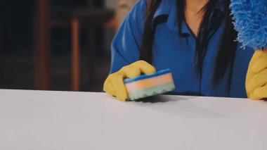 Evi temizliyorum. Yakın plan - mavi lastik eldivenli bir kadın ve mavi lastik eldivenli sarı bir paçavra temizlik yapıyor.