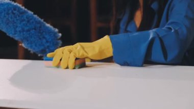 Mavi eldivenli kadın evi temizliyor.