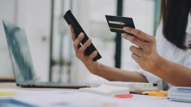 İnternetten alışveriş yapmak için kredi kartı ve dizüstü bilgisayar kullanan Asyalı genç bir kadın..