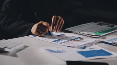 İşadamı finansal tabloları analiz ediyor ve ofisteki bilgisayarı kullanıyor.