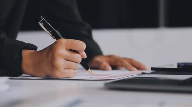 Belgeler ve kalemle ofis masasında çalışan işadamı.