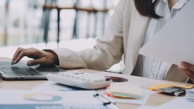 İş kadınlarının hesap makinesini kullanarak ofis bilgisayarındaki bilgisayar, mali muhasebe ve araştırma raporlarını analiz etmesi.
