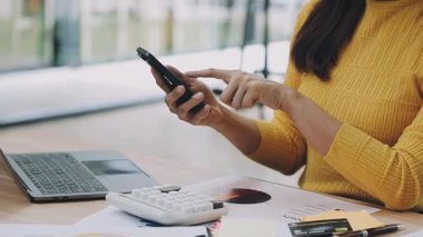 Akıllı telefon kullanan ve bilgisayar üzerinde çalışırken not yazan iş kadınlarının kapatılması