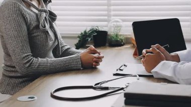 Hasta masasında oturup sağlık sigortasıyla görüşen doktorların ellerini kapatın..