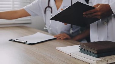 Doktor steteskop tutuyor, ofiste reçete yazıyor..