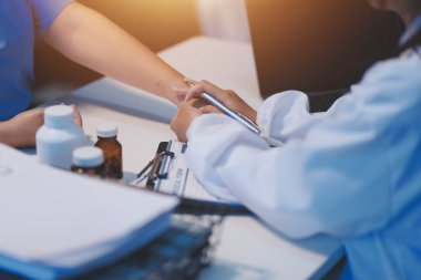 Doktor umut veriyor. Genç kadın hekimin avuçlarında elini tutan yaşlı bayanın gülümsemesini yakından çek. Beyaz önlüklü kadın bakıcı yaşlı insanı cesaretlendiriyor.