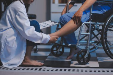 Asyalı, genç, profesyonel, dost canlısı mavi hastane üniformalı kadın hemşire yaşlı, yaşlı, sağlıksız, dört bacaklı, yürüyen bir hastanın fiziksel terapisine yardım ediyor..