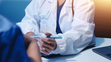 Doktor umut veriyor. Genç kadın hekimin avuçlarında elini tutan yaşlı bayanın gülümsemesini yakından çek. Beyaz önlüklü kadın bakıcı yaşlı insanı cesaretlendiriyor.