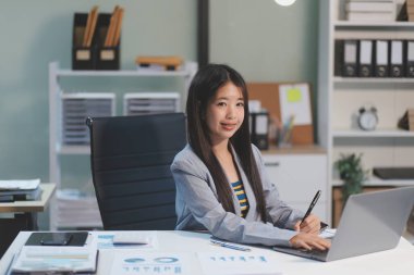 Ofiste dizüstü bilgisayarda çalışan neşeli iş kadını, iş yerinde resmi takım elbiseli Asyalı mutlu iş kadını. Çekici bayan ofis çalışanı gülümsemesi.