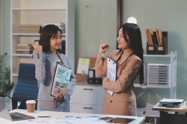 Dijital tablet üzerinde çalışan iki genç kadının fotoğrafı. Yaratıcı kadın yöneticiler ofiste buluşup tablet bilgisayar kullanıyor ve gülümsüyor..