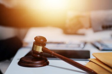 Avukat, müvekkil ile evraklar, sözleşmeler, anlaşmalar, iş birliği anlaşmaları hakkında el sıkışıyor avukatın masasında bir kadın müvekkil ve masada bir çekiç.