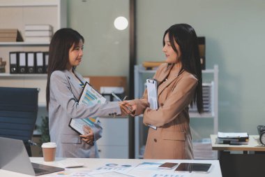 Dijital tablet üzerinde çalışan iki genç kadının fotoğrafı. Yaratıcı kadın yöneticiler ofiste buluşup tablet bilgisayar kullanıyor ve gülümsüyor..