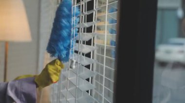 Kadın tuvalette süngerle pencereyi temizliyor.