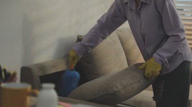 Genç Asyalı adam oturma odasında ev işi yapıyor.