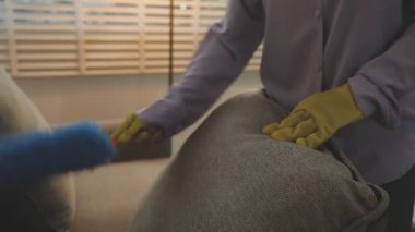 Sarı eldivenli bir kadın evi temizliyor.