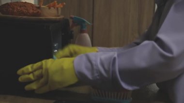 Eldivenli kadın mutfağı temizliyor.