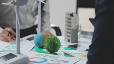 Yeşil bir küre tutan bir iş adamı ve bir kalemle Dünya gezegeni.