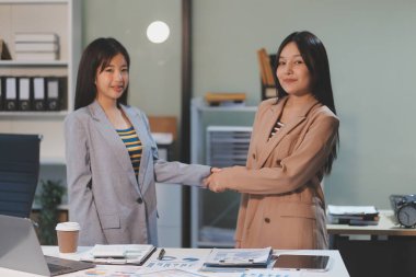 Ofis toplantısı sırasında el ele tutuşan kendine güvenen iki iş kadını. Başarı. Yöneticiler. İş arkadaşları ayakta alkışlıyor. Tebrikler takım çalışması..