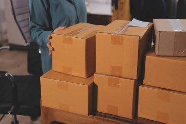 Girişim KOBİ küçük işletme girişimcisi önlük giyen Asyalı kadın dizüstü bilgisayar ve kutu kullanarak çevrimiçi müşterilere, çevrimiçi sme iş fikirlerine satış hazırlamak için siparişleri alır ve gözden geçirir.