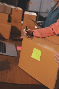 Girişim KOBİ küçük işletme girişimcisi önlük giyen Asyalı kadın dizüstü bilgisayar ve kutu kullanarak çevrimiçi müşterilere, çevrimiçi sme iş fikirlerine satış hazırlamak için siparişleri alır ve gözden geçirir.