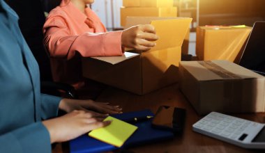 Girişim KOBİ küçük işletme girişimcisi önlük giyen Asyalı kadın dizüstü bilgisayar ve kutu kullanarak çevrimiçi müşterilere, çevrimiçi sme iş fikirlerine satış hazırlamak için siparişleri alır ve gözden geçirir.