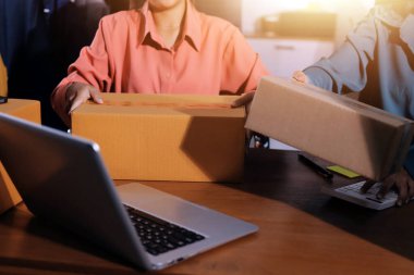 Girişim KOBİ küçük işletme girişimcisi önlük giyen Asyalı kadın dizüstü bilgisayar ve kutu kullanarak çevrimiçi müşterilere, çevrimiçi sme iş fikirlerine satış hazırlamak için siparişleri alır ve gözden geçirir.