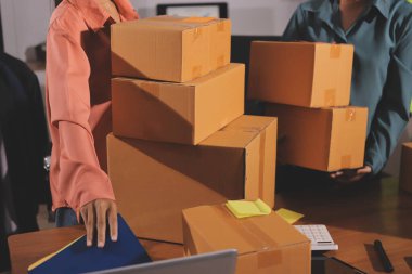 Girişim KOBİ küçük işletme girişimcisi önlük giyen Asyalı kadın dizüstü bilgisayar ve kutu kullanarak çevrimiçi müşterilere, çevrimiçi sme iş fikirlerine satış hazırlamak için siparişleri alır ve gözden geçirir.