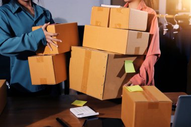 Girişim KOBİ küçük işletme girişimcisi önlük giyen Asyalı kadın dizüstü bilgisayar ve kutu kullanarak çevrimiçi müşterilere, çevrimiçi sme iş fikirlerine satış hazırlamak için siparişleri alır ve gözden geçirir.